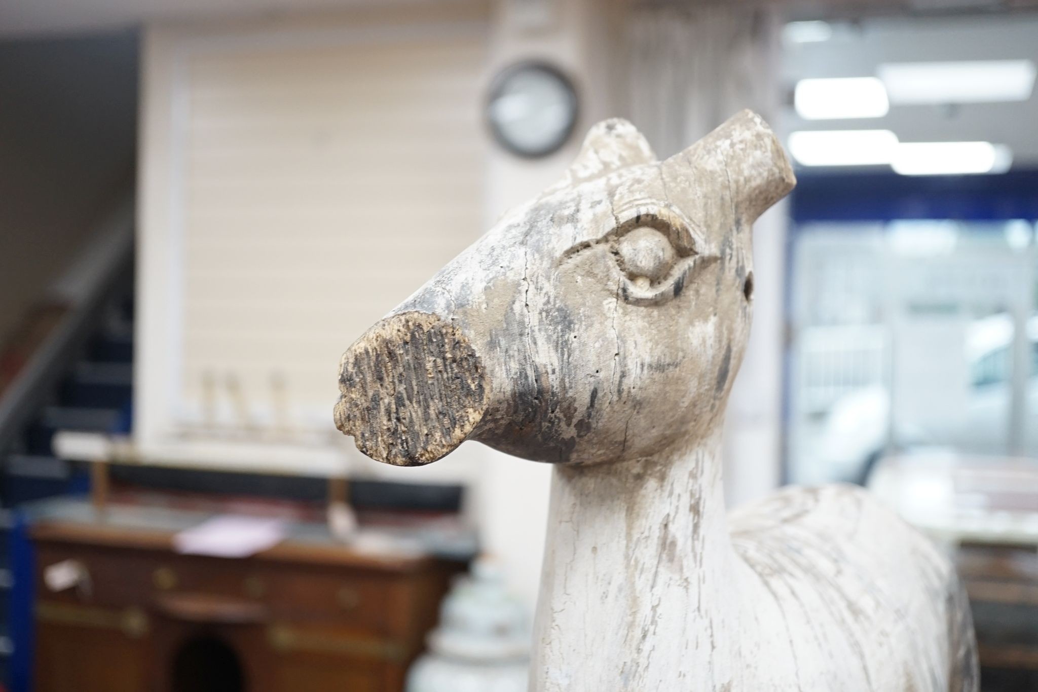 A carved and painted wood model of a goat, with distressed paint, on stand. 66cm